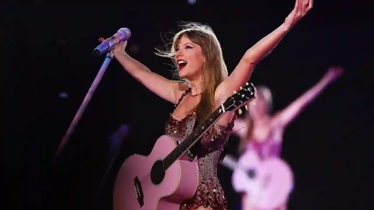 Taylor Swift lächelnd mit ihrer Gitarre auf der Bühne