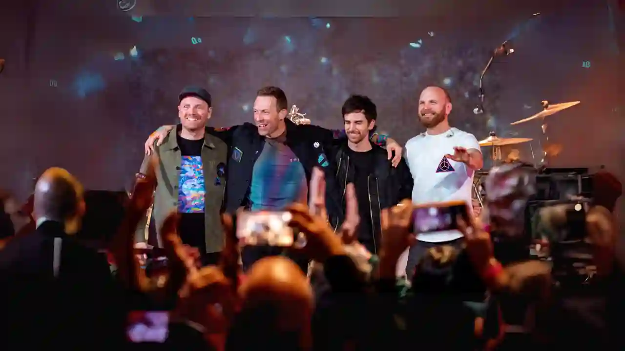 Chris Martin, Jonny Buckland, Will Champion und Guy Berryman von Coldplay auf der Bühne zu ihren Fans gerichtet.